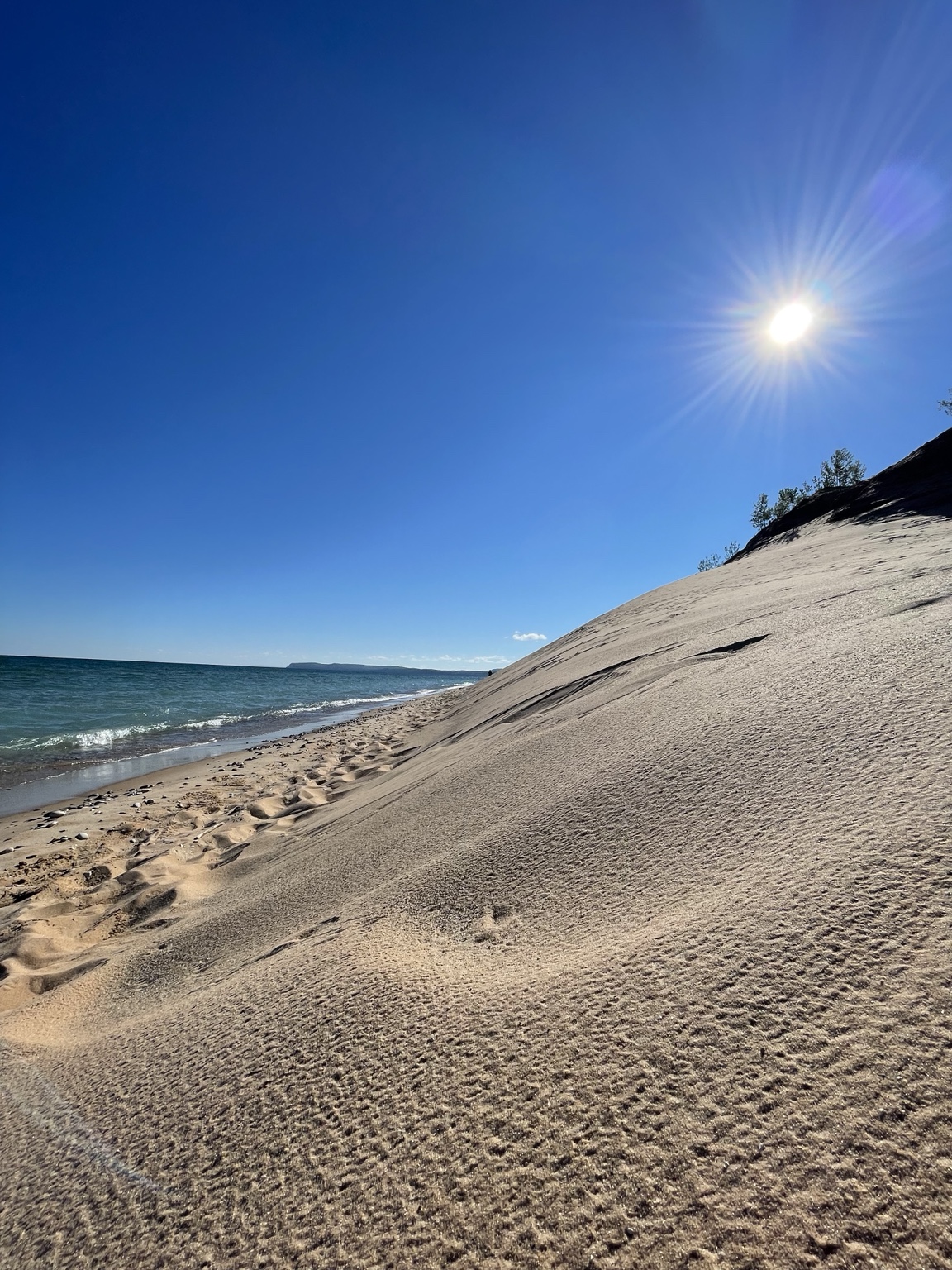 Sun over a dune meeting the blue water of Lake Michigan